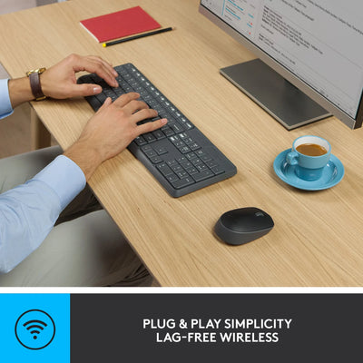 Person using a wireless keyboard at a desk with a computer monitor, mouse, and coffee cup.